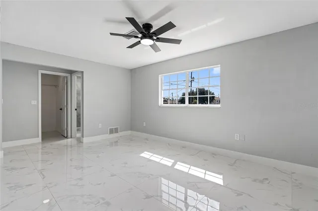 an empty room with windows and fan