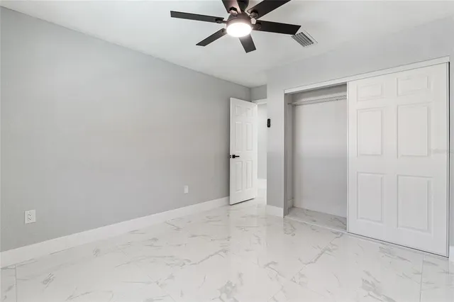 an empty room with closet and a chandelier fan