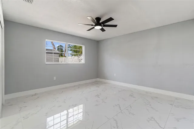 an empty room with windows and ceiling fan