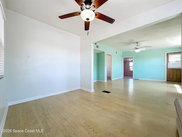 a view of an empty room with window and a ceiling fan