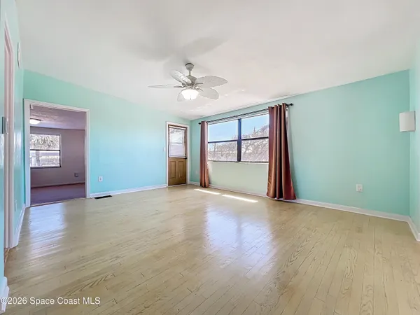 a view of empty room with wooden floor and fan