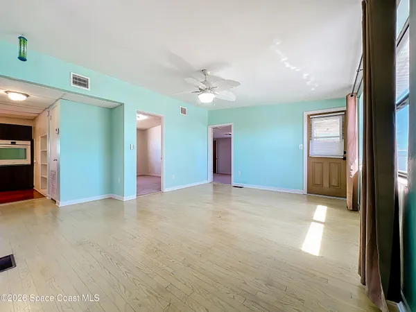 an empty room with chandelier fan and windows