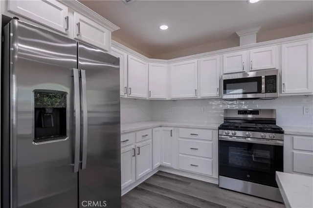 a kitchen with stainless steel appliances white cabinets and a stove top oven