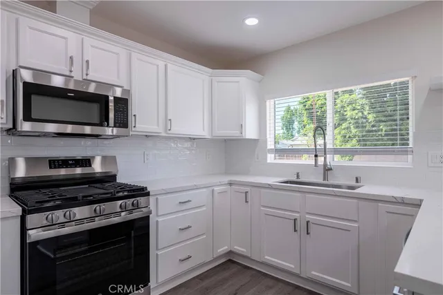 a kitchen with cabinets appliances a sink and a window