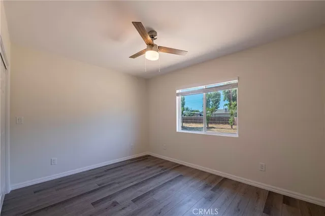 an empty room with wooden floor fan and windows