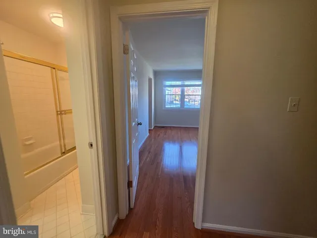 a view of a hallway with wooden floor and closet area