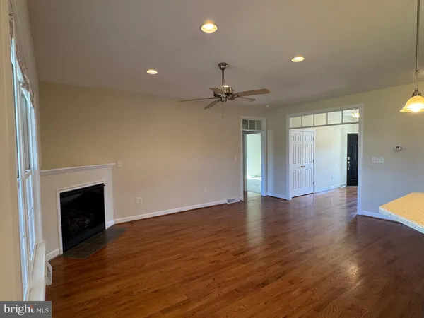 a view of an empty room with wooden floor fireplace and a window