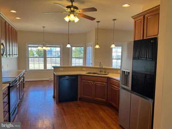 a kitchen with stainless steel appliances granite countertop a refrigerator a sink dishwasher a stove and white countertops with wooden floor