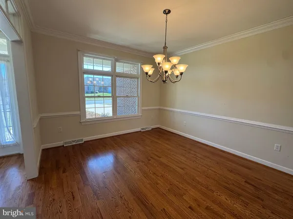 a view of a room with wooden floor chandelier and windows