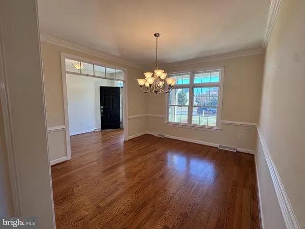 a view of a room with wooden floor chandelier and windows