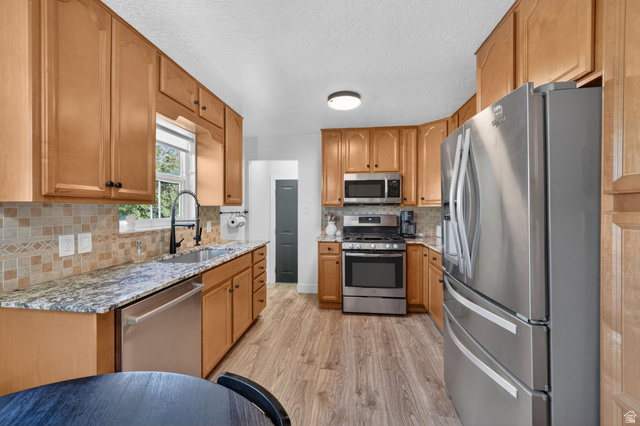 66 South 425 West Bountiful, UT 84010 - Photo 10 of 25 Spacious kitchen featuring wood cabinetry, stainless steel appliances, granite countertops, tile backsplash, and wood-finish flooring