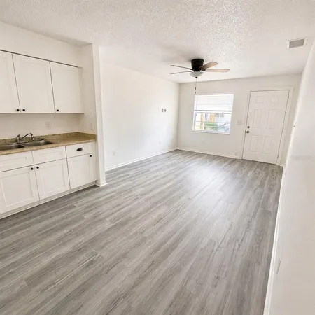 an empty room with wooden floor cabinet and windows