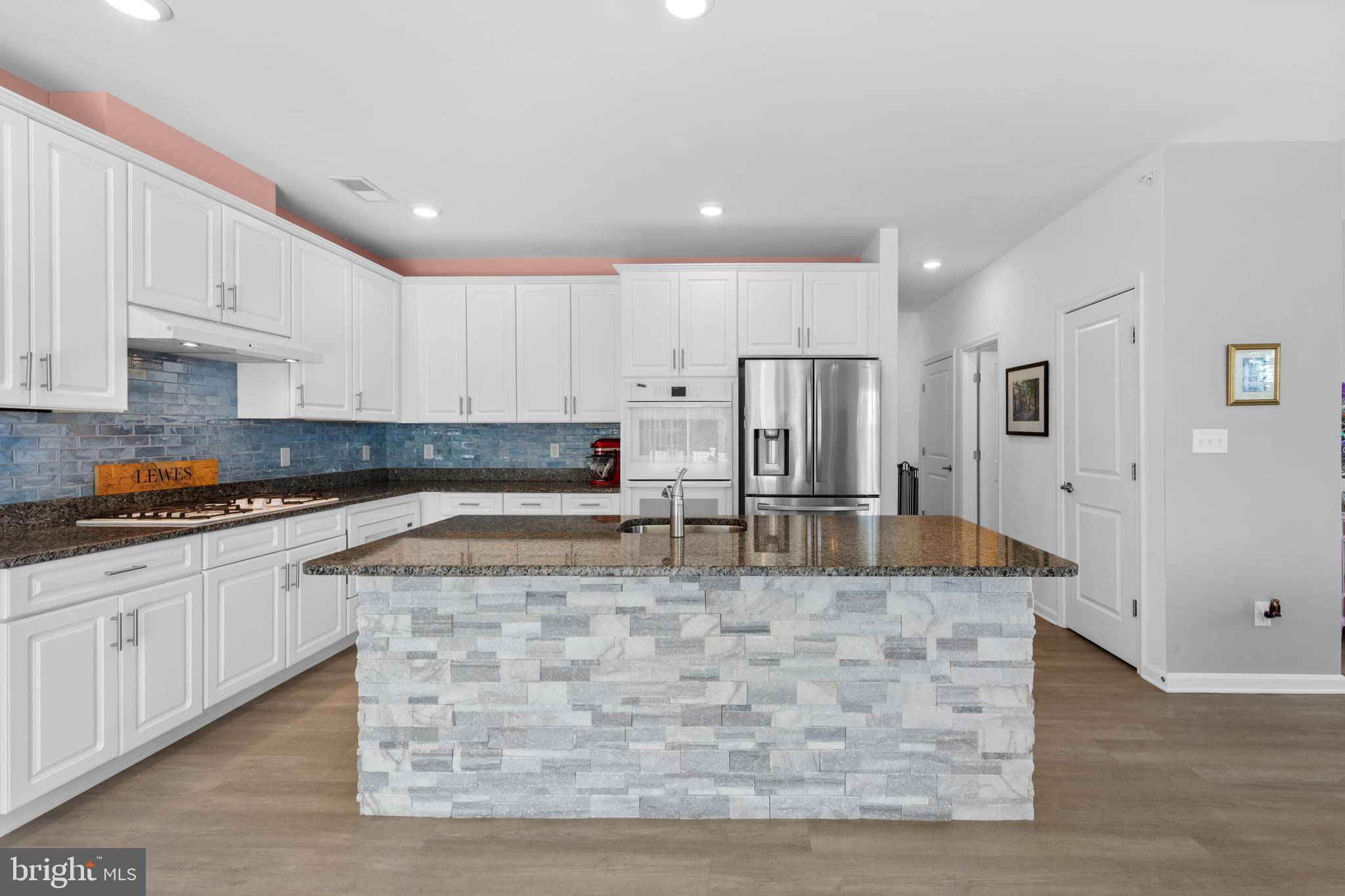 24525 Merlot Drive Lewes, DE 19958 - Photo 19 of 40 a large kitchen with stainless steel appliances granite countertop a stove a sink a refrigerator white cabinets and a granite countertops