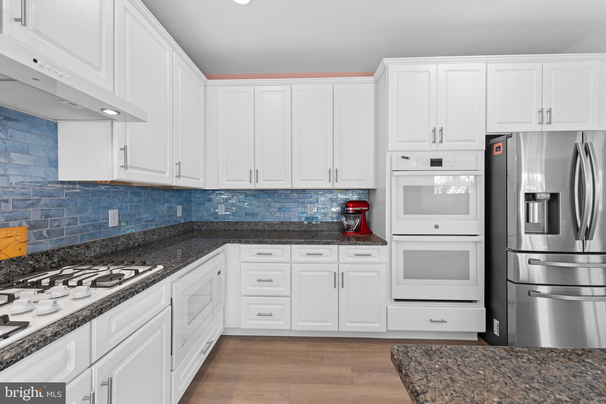 24525 Merlot Drive Lewes, DE 19958 - Photo 20 of 40 a kitchen with granite countertop a refrigerator stove and white cabinets