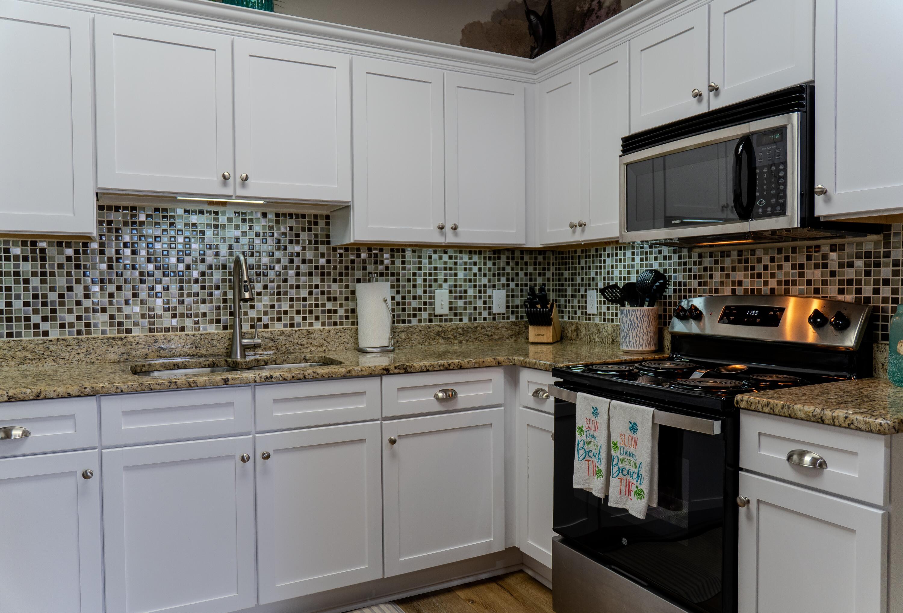 136 Shorebird Drive, Unit 724 Santa Rosa Beach, FL 32459 - Photo 16 of 49 a kitchen with granite countertop white cabinets and black appliances