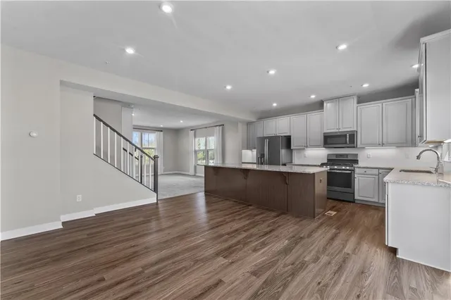 a kitchen with stainless steel appliances granite countertop a stove top oven a sink and a refrigerator