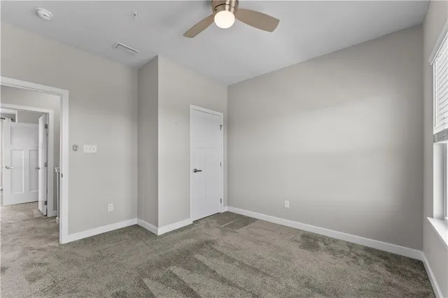 an empty room with a ceiling fan and carpet