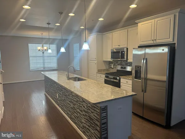 a kitchen with kitchen island granite countertop a refrigerator a sink a stove and wooden cabinets