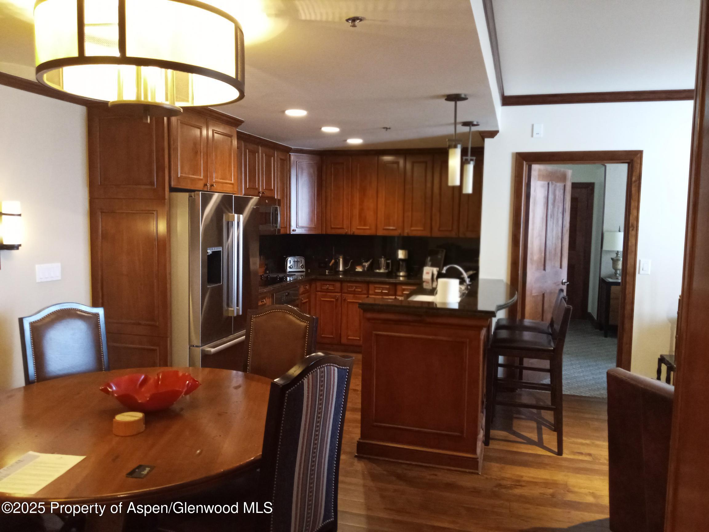 75 Prospector Road, Unit 8408 WINTER INTEREST #6 Aspen, CO 81611 - Photo 26 of 32 a kitchen with stainless steel appliances granite countertop a sink dishwasher and a refrigerator with wooden floor