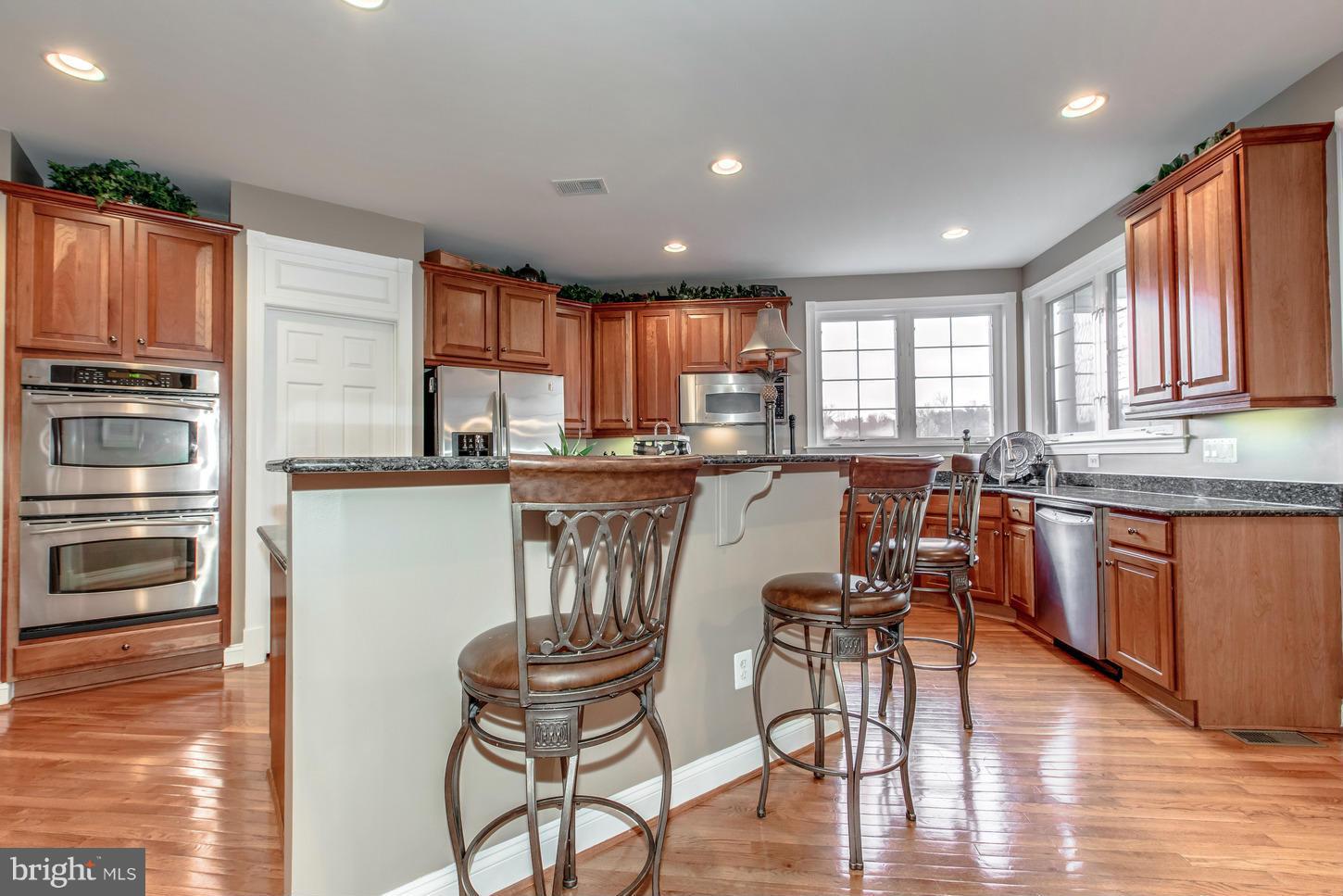 1152 Markell Court Reston, VA 20194 - Photo 8 of 30 a kitchen with stainless steel appliances granite countertop a stove a sink a refrigerator white cabinets and wooden floor