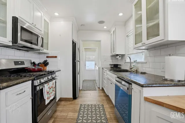 a kitchen with stainless steel appliances granite countertop a stove a sink and a microwave