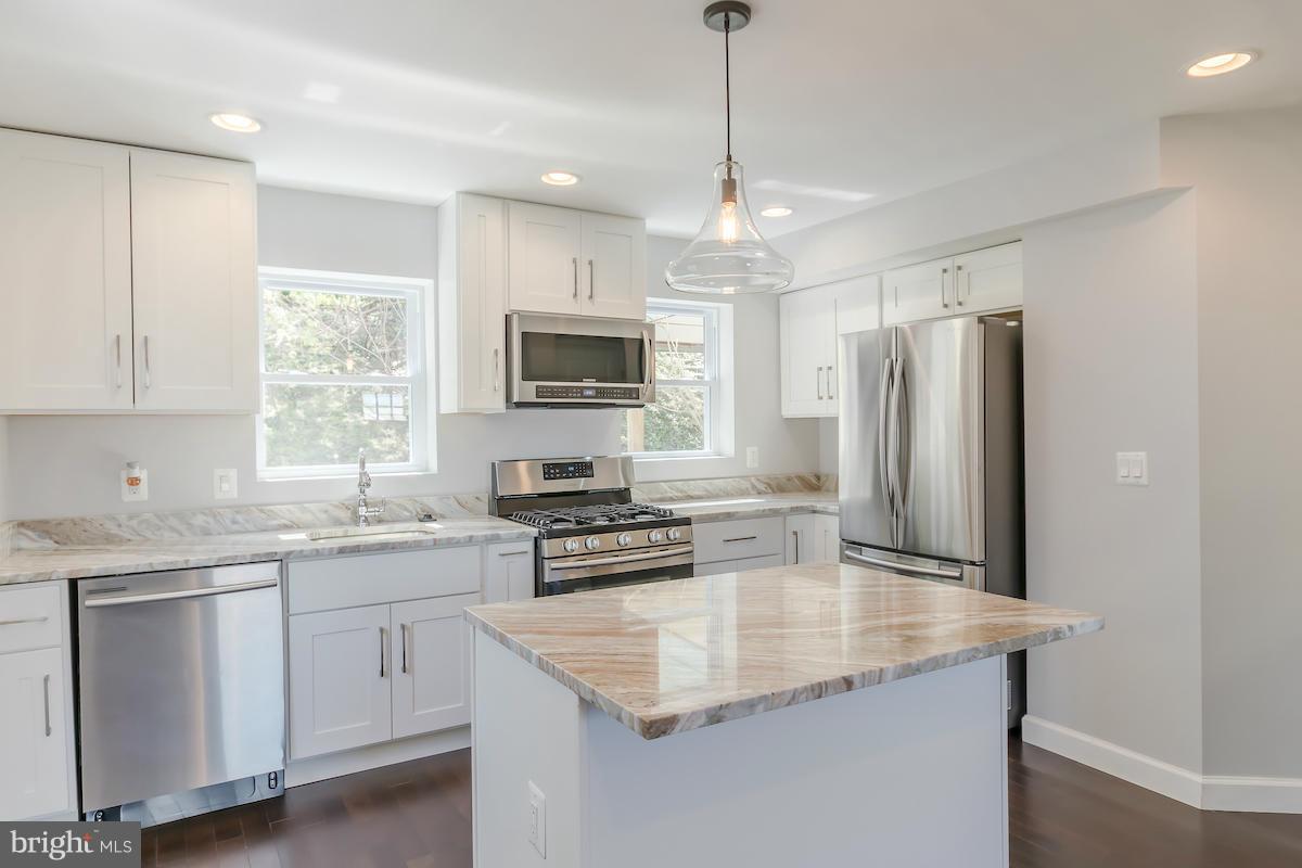 5093 Sheriff Road Northeast Washington, DC 20019 - Photo 5 of 14 a kitchen with stainless steel appliances granite countertop a sink a stove a refrigerator cabinets and a window