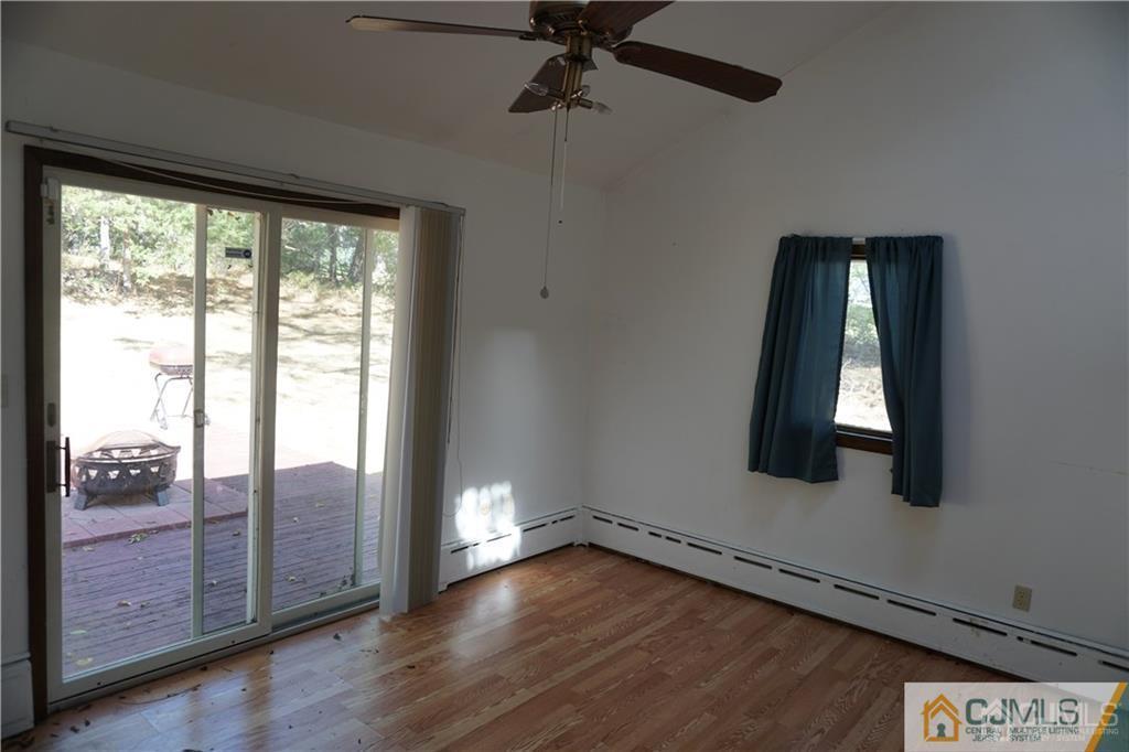 634 Old Stage Road East Brunswick, NJ 08816 - Photo 4 of 17 an empty room with wooden floor fan and windows