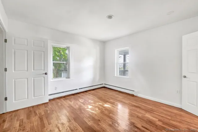 a view of empty room with wooden floor and fan