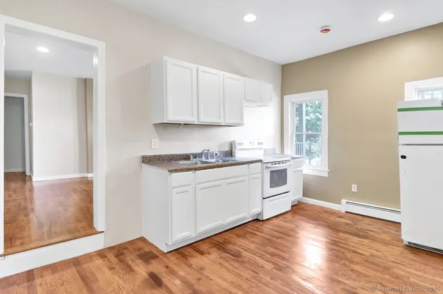 a kitchen with granite countertop white cabinets and white appliances