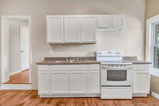 a kitchen with granite countertop white cabinets and white appliances