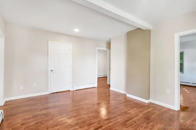 an empty room with wooden floor & windows and bathroom