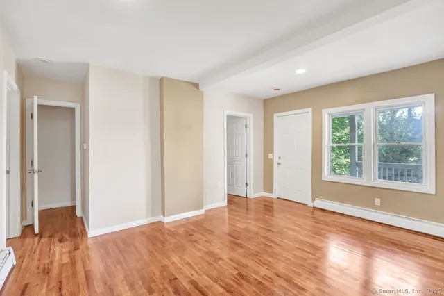 a view of an empty room with wooden floor and a window