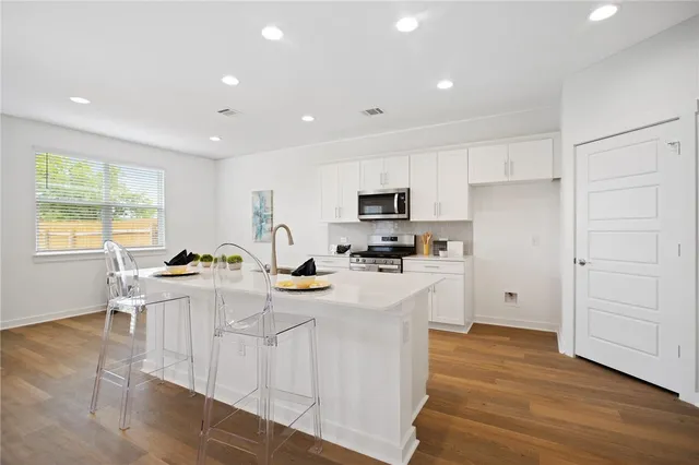 a kitchen with a sink a stove a refrigerator cabinets and wooden floor
