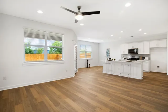 a view of kitchen with kitchen island stainless steel appliances wooden floor cabinets and a window