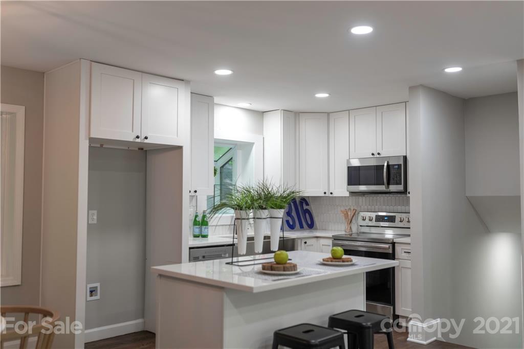 7316 Watercrest Road Charlotte, NC 28210 - Photo 11 of 28 a kitchen with kitchen island white cabinets a refrigerator and a stove with wooden floor