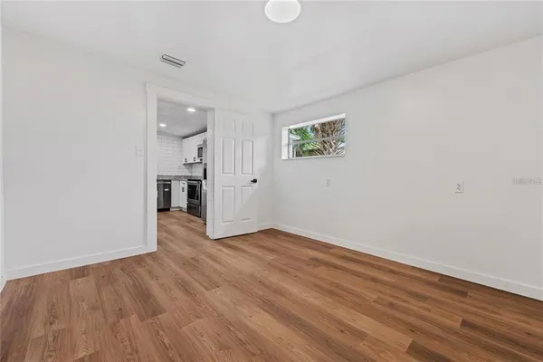 a view of an empty room with wooden floor and a window