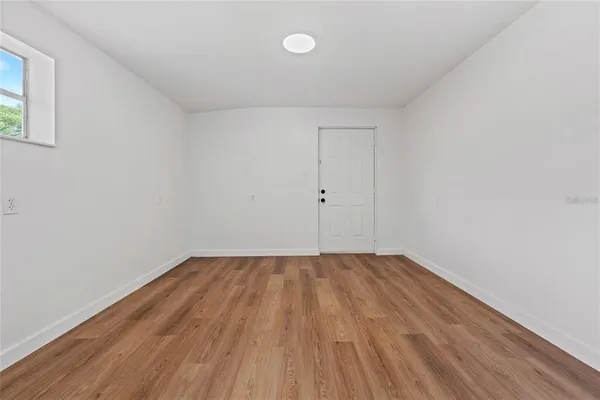 a view of an empty room with wooden floor and a window