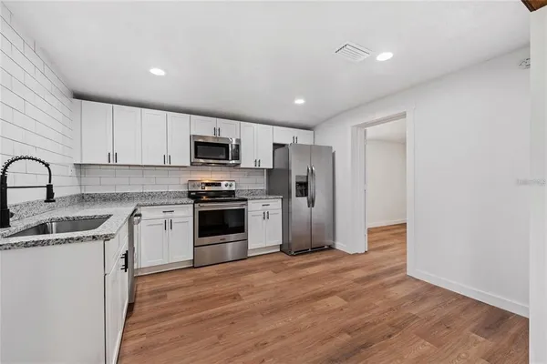 a kitchen with granite countertop a refrigerator and a stove top oven