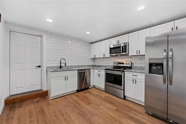 a kitchen with granite countertop a refrigerator stove top oven and sink