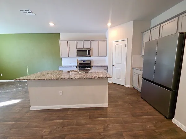 a kitchen with stainless steel appliances granite countertop a refrigerator a stove a sink and a refrigerator