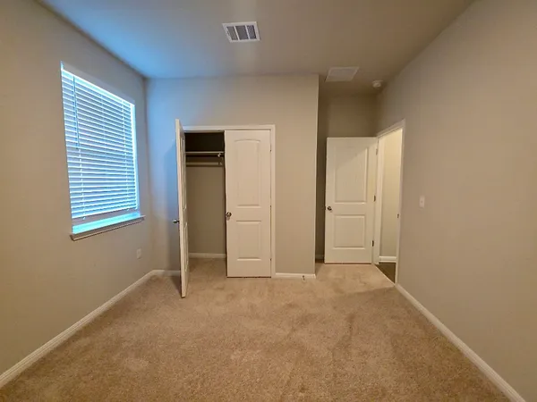a view of an empty room with closet and a window