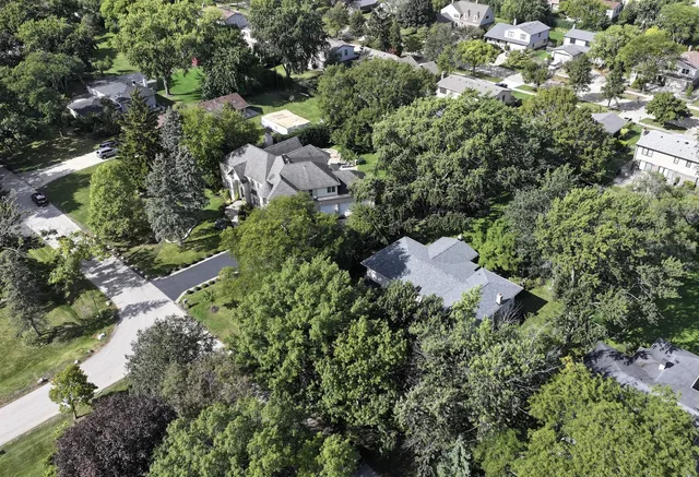 an aerial view of residential house with outdoor space and trees all around