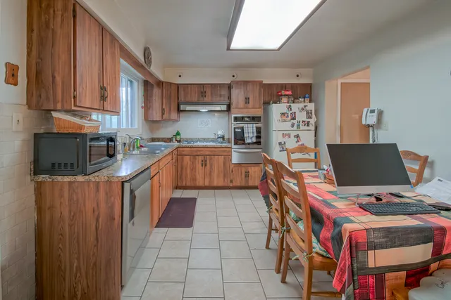 a kitchen with stainless steel appliances a stove top oven a sink a dining table and chairs