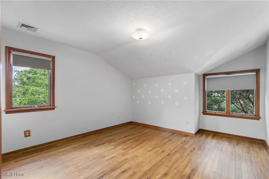 2317 Raintree Street Northeast Canton, OH 44705 - Photo 24 of 40 Bonus room with lofted ceiling, light wood-style flooring, and a textured ceiling