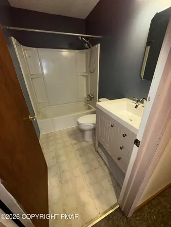 a view of an empty room with window and chandelier fan