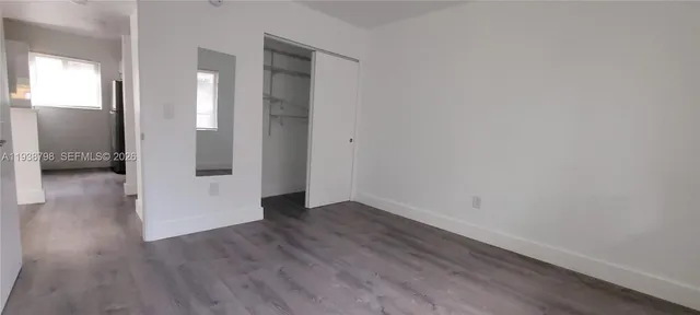 a view of an empty room with wooden floor and a bathroom