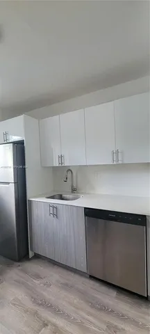 a kitchen with stainless steel appliances a sink a refrigerator and white cabinets