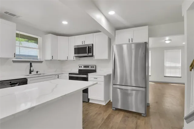 a kitchen with a refrigerator a microwave a sink and cabinets
