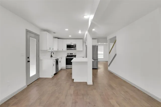 a view of kitchen with stainless steel appliances refrigerator oven and white cabinets