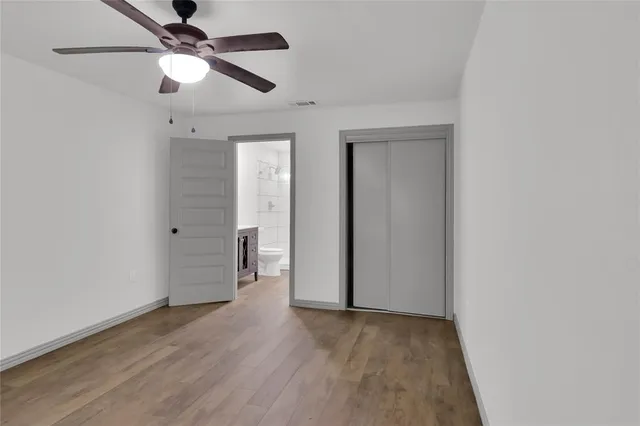 an empty room with wooden floor ceiling fan and closet area